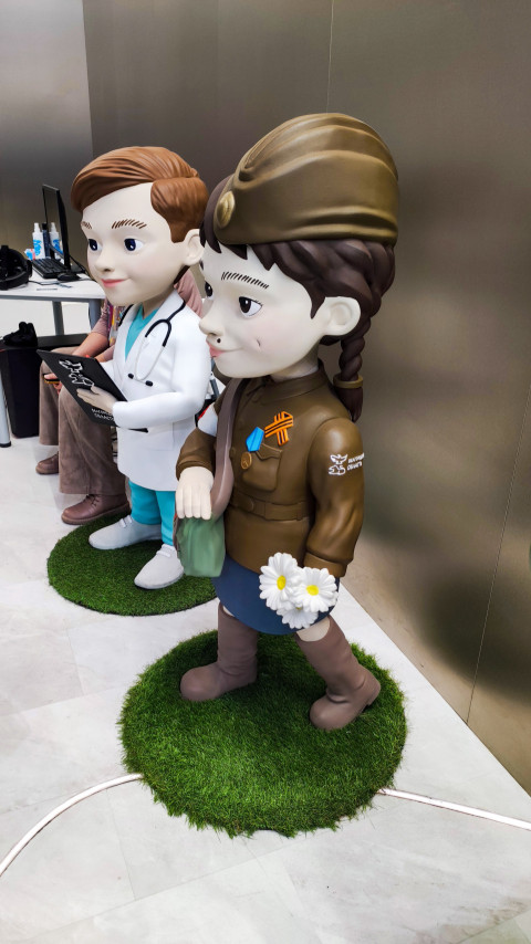 Фигуры ребёнка-медика и девочки в военной форме на стенде Белгородской области