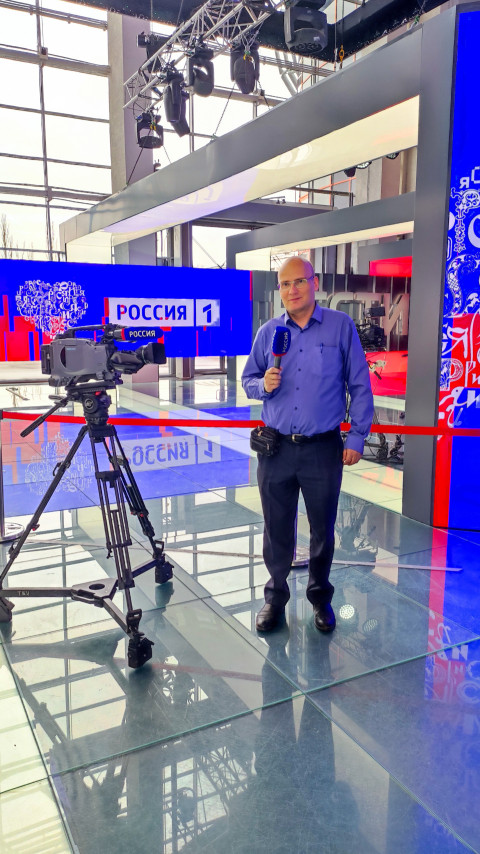 Репортёр у телекамеры на стенде «Россия 1»