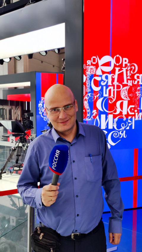 Посетитель с микрофоном «Россия» на фоне телестудии ВДНХ