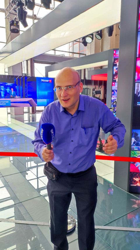 Посетитель с микрофоном «Россия» на фоне телестудии в экспозиции ВДНХ