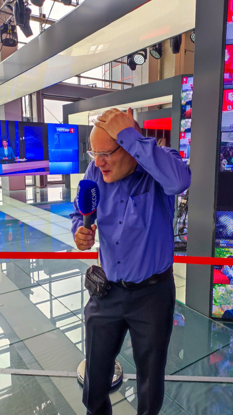 Мужчина с микрофоном у зоны вещания телеканала «Россия 1»