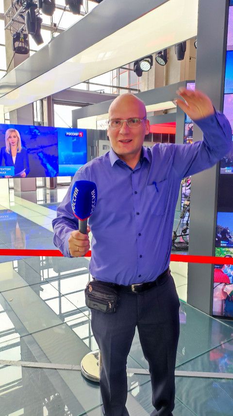 Мужчина с микрофоном «Россия» в павильоне выставки