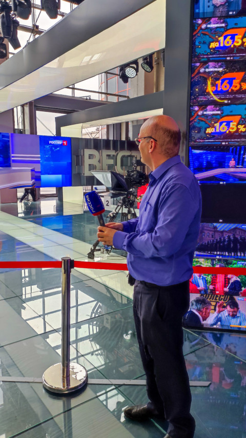 Посетитель с микрофоном перед телевизионной камерой