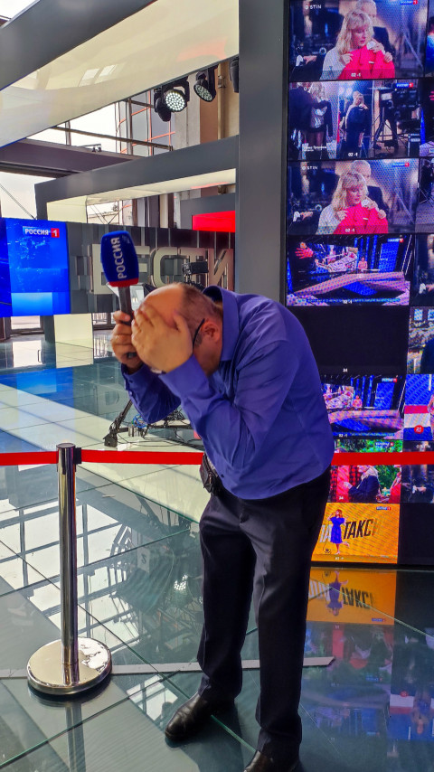 Человек с микрофоном приседает в медиа-зоне выставки