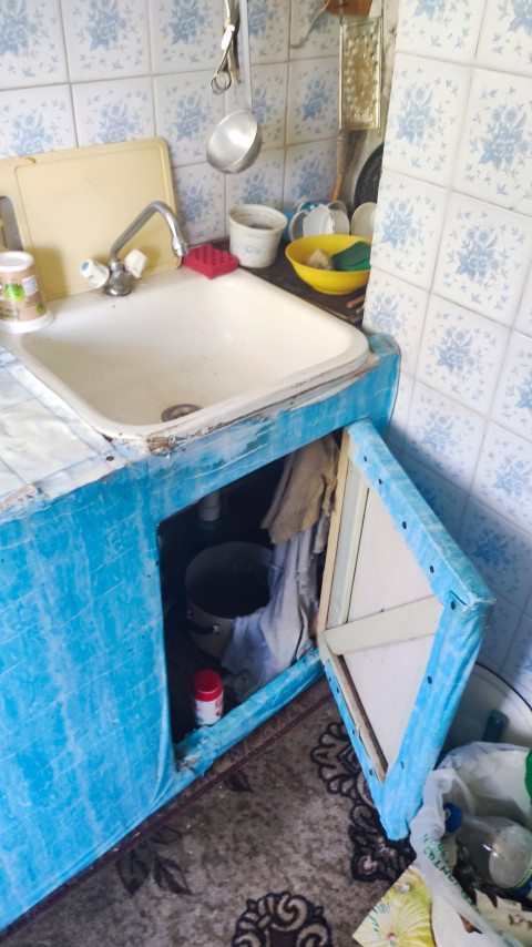 Кухонная раковина с открытой тумбой и посудой на рабочей поверхности