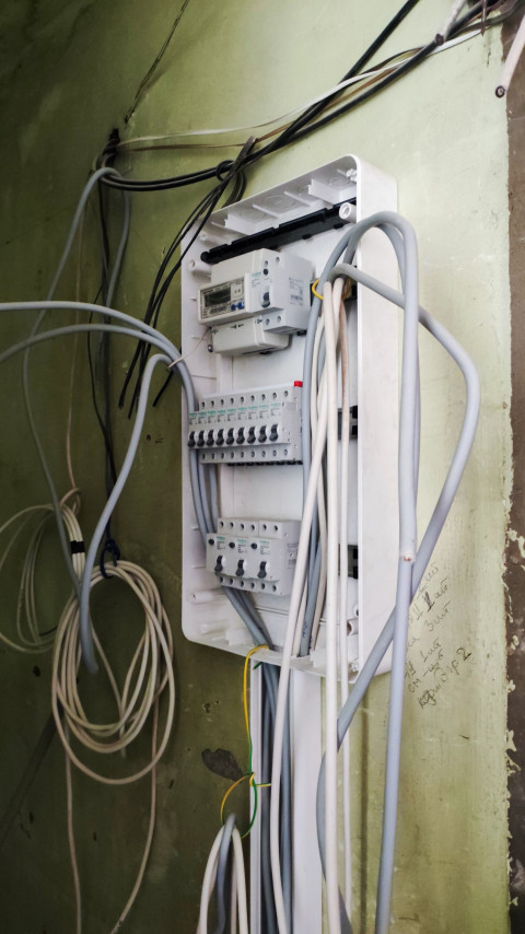 Распределительный электрощит с подключёнными кабелями в помещении ремонта