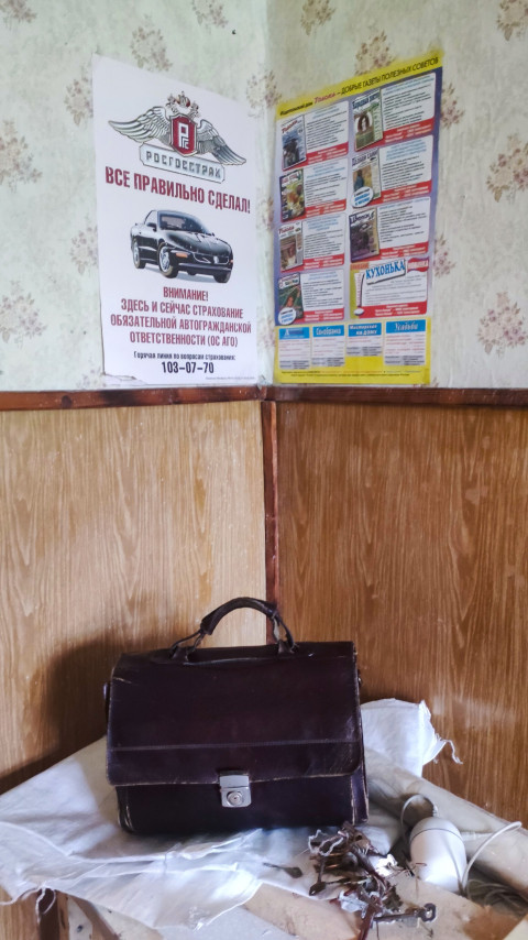 Постеры на стене и кожаный портфель с ключами на столе в старом помещении