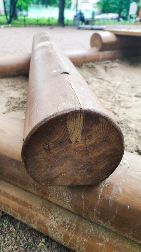 Торец бревна ограждения песочницы с годичными кольцами и трещиной