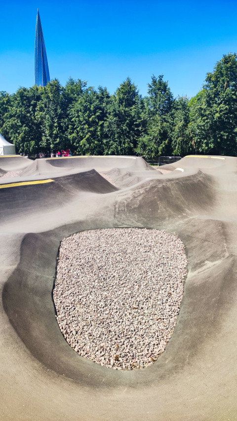 Чаша памп-трека с гравийной вставкой на фоне деревьев и Лахта Центра