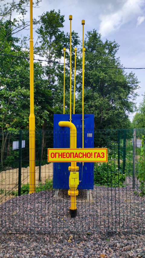 Желтый газопровод и знак «Огнеопасно! Газ» у синего шкафа оборудования