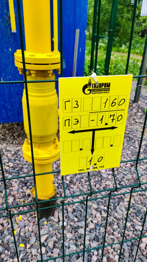 Табличка Газпром на ограждении рядом с жёлтой арматурой газопровода