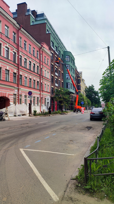 Улица с историческим и современным фасадами и подъёмной платформой для работ на высоте