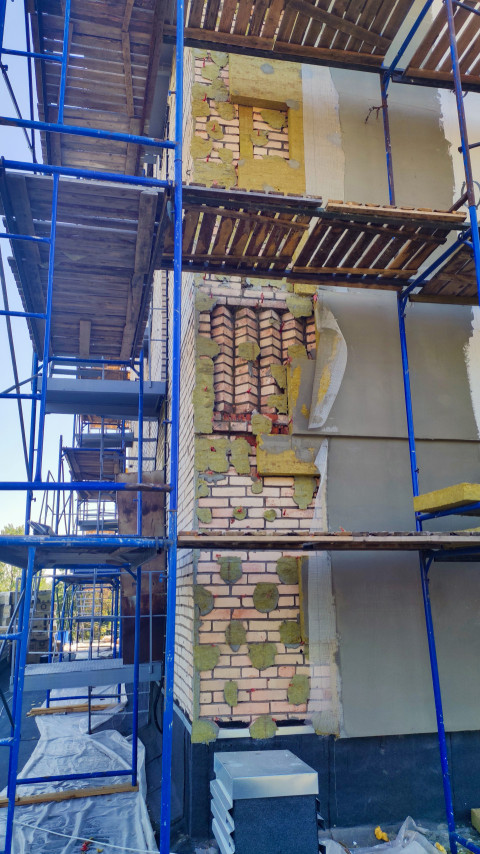 Утепление фасада на строительных лесах с видимой кирпичной кладкой и минватой под армирующей сеткой