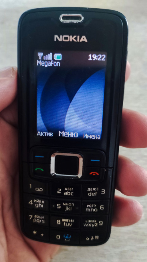 Телефон Nokia в руке с экраном ожидания и временем 19:22 на дисплее