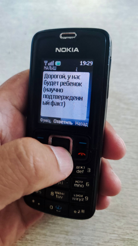 Крупный план телефона Nokia с SMS о будущем ребенке и нажатием кнопки пальцем