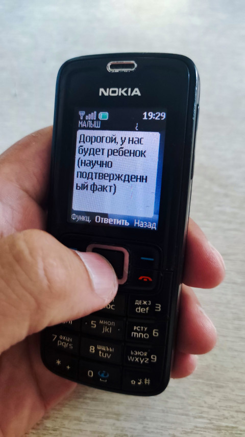 Телефон Nokia в руке с открытым SMS и заметной кнопкой ответа на экране