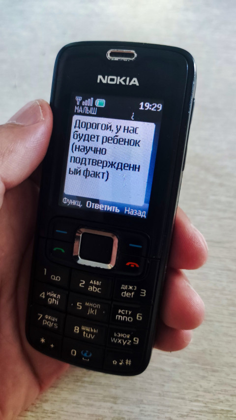 Кнопочный телефон Nokia с SMS о беременности и видимой цифровой клавиатурой в кадре