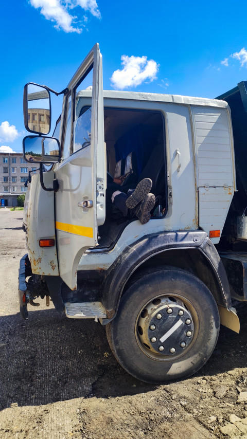 Кабина самосвала и переднее колесо грузовика на строительной площадке крупным планом