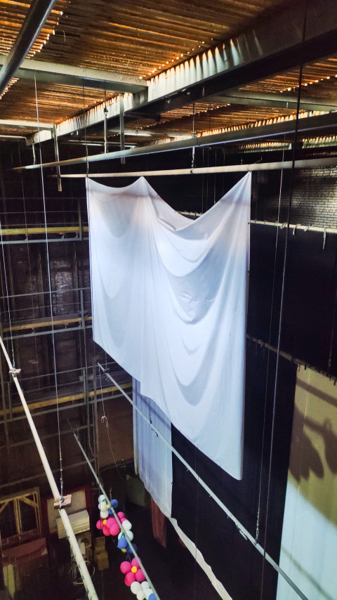 Подвешенное белое полотно под потолочными балками в кирпичном зале с тросами и шарами