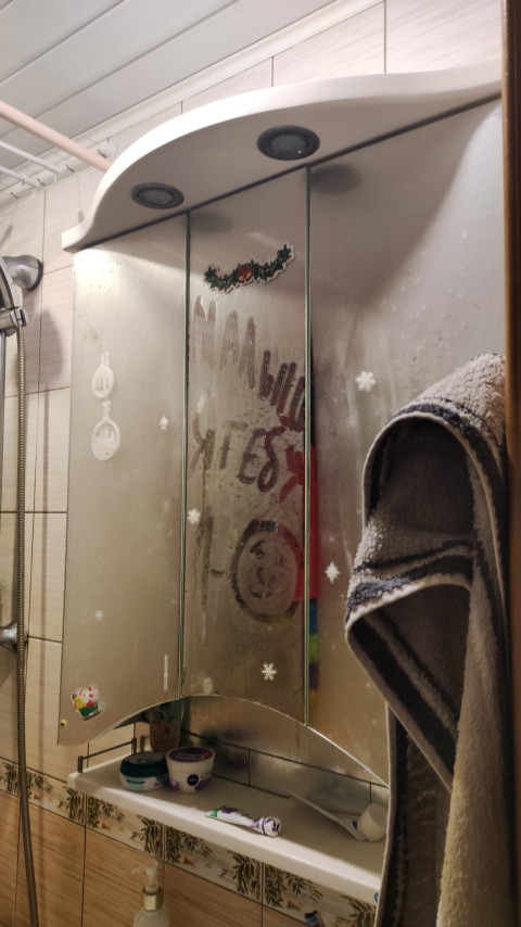 Запотевшее зеркальце в ванной с рисунками пальцем отражает обычное утро дома