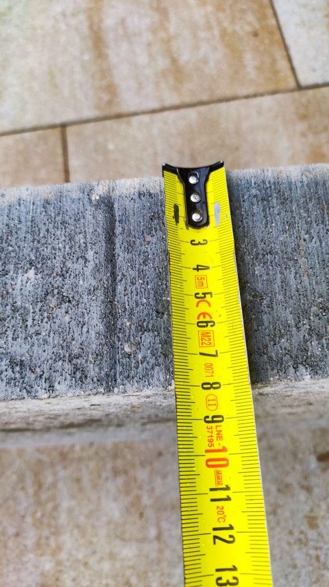 Измерение толщины бетонного бордюра рулеткой у кромки изделия