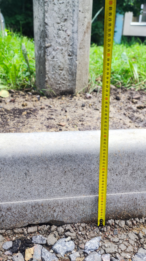 Рулетка у бетонного бордюра при контрольном измерении высоты