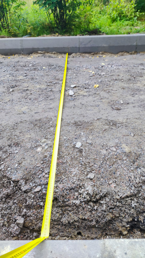 Рулетка, вытянутая по щебёночному основанию вдоль бордюрного камня