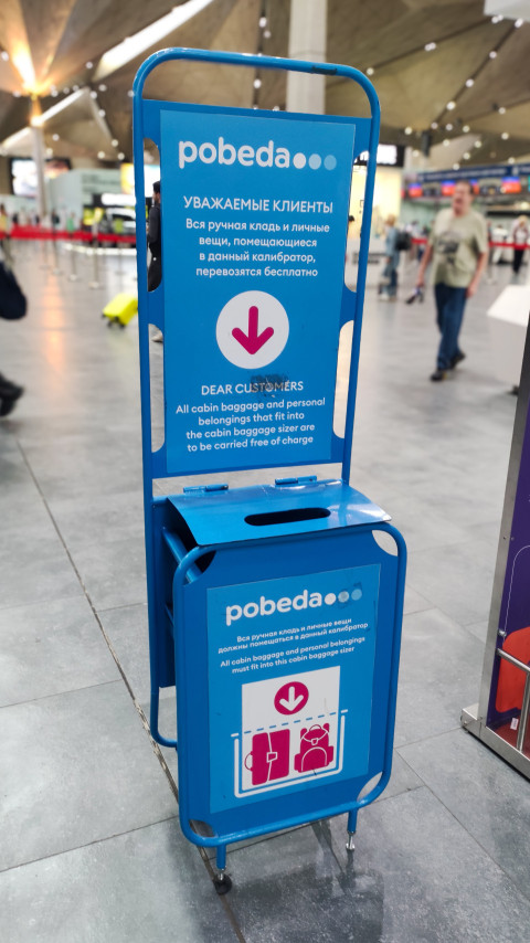 Калибратор ручной клади Победы на фоне стоек регистрации