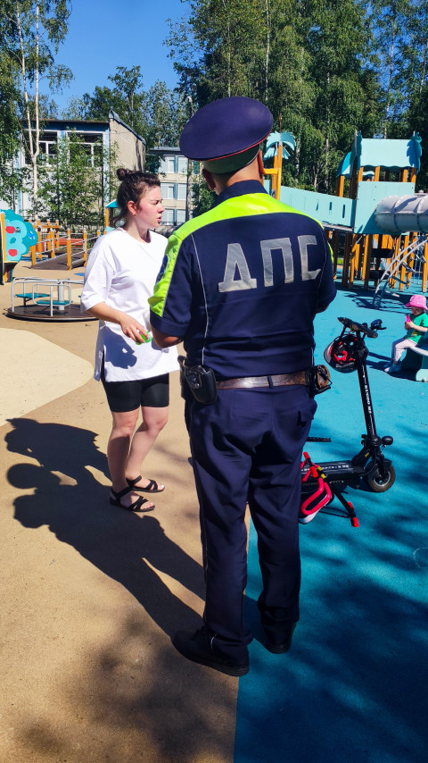 Сотрудник ДПС беседует с женщиной на детской площадке рядом с электросамокатом