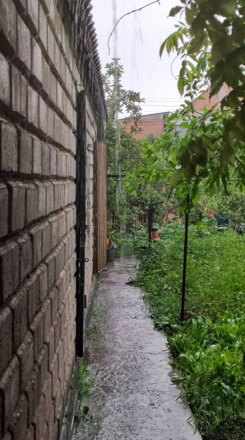 Поток дождевой воды вдоль кирпичной стены дома