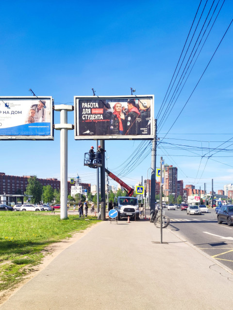 Рабочие на подъемнике у рекламного щита на городской улице