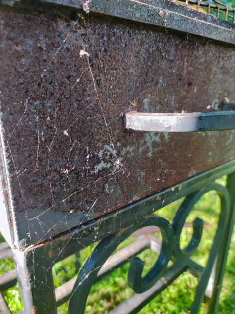 Ржавый бок мангала с ручкой и паутиной, крупный план