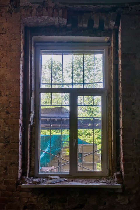 Окно с решёткой в кирпичной стене здания во время ремонта