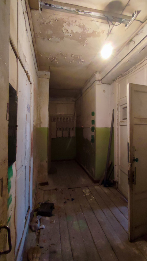 Коридор с открытой дверью, оголённой проводкой и лампочкой под потолком