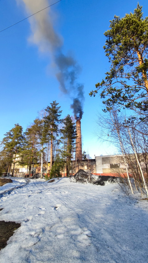 Заводская труба с дымом на фоне голубого неба