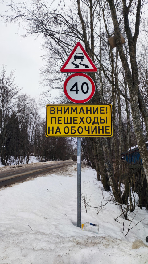 Дорожные знаки на фоне зимней лесной дороги