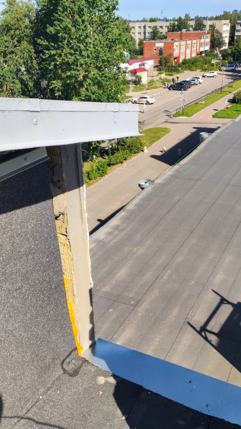 Кромка плоской крыши с открытым утеплителем и видом на городскую улицу